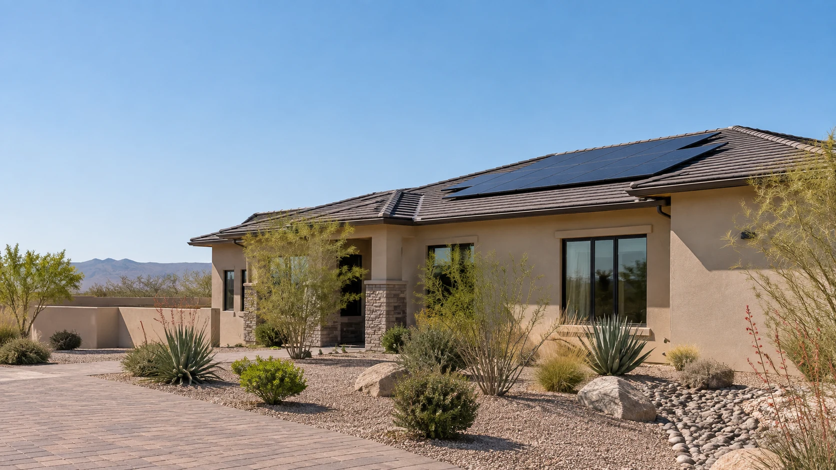 Rectangular solar array on a low beige home beside a gravel courtyard