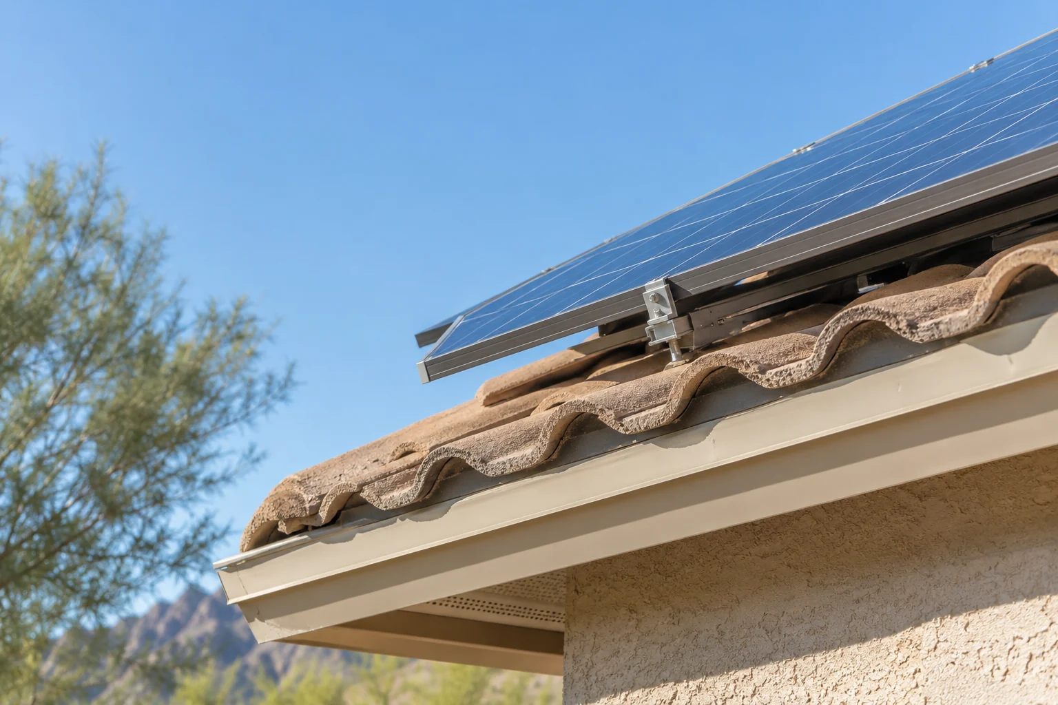 Low angle view of a solar panel frame and mounting rail above a desert home roof edge